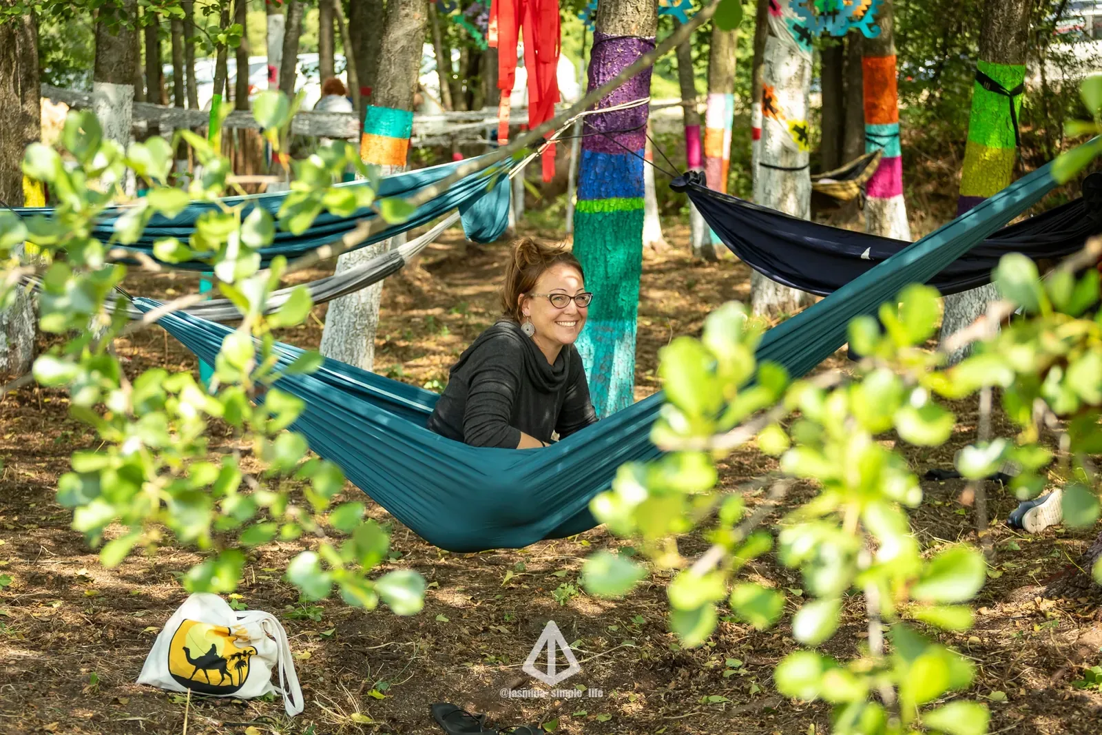 A guest resting in a hammock between painted trees in the grove