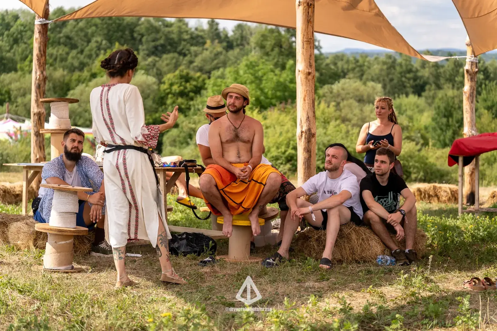 Grupa razgovara u hladu tende na livadi